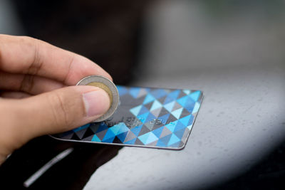 Cropped hand holding coin on credit card