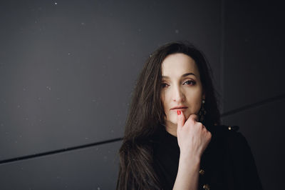 Portrait of young woman standing by wall