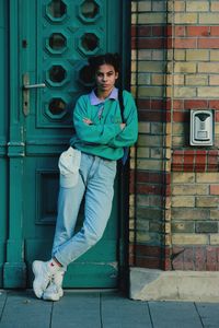 Portrait of young woman standing against closed door