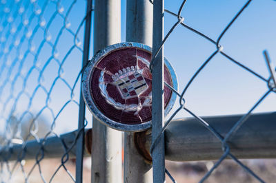 Close up of cadillac emblem on chainlink fence