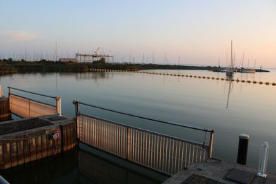 Pier over river against sky during sunset