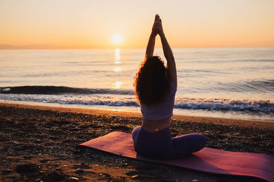 Side view of woman doing yoga at beach during sunset