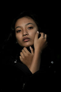 Portrait of young woman against black background