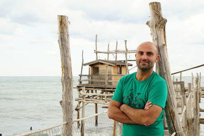 Portrait of bald man standing on pier over sea