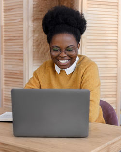 Smiling businesswoman using laptop at office