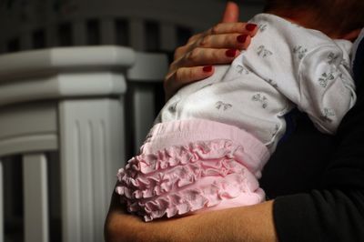 Mother caring baby girl in arms at home