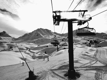 Ski lift over snowcapped mountains against sky