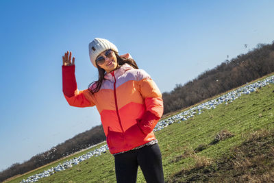 Young woman standing on field against clear sky