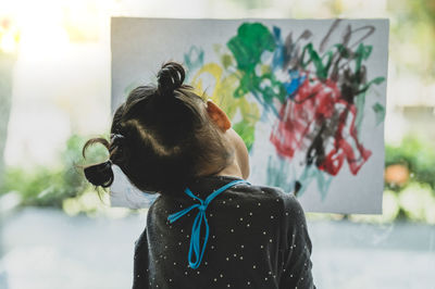 Rear view of girl painting on paper