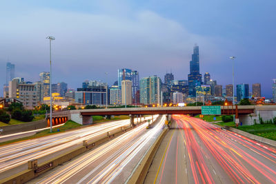 High angle view of light trails on highway in city against sky