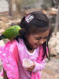 High angle view of cute girl carrying parrot on shoulder