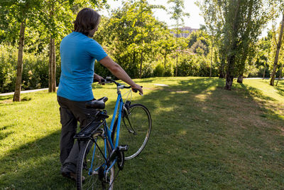 Unrecognizable man walking in the park with his bicycle