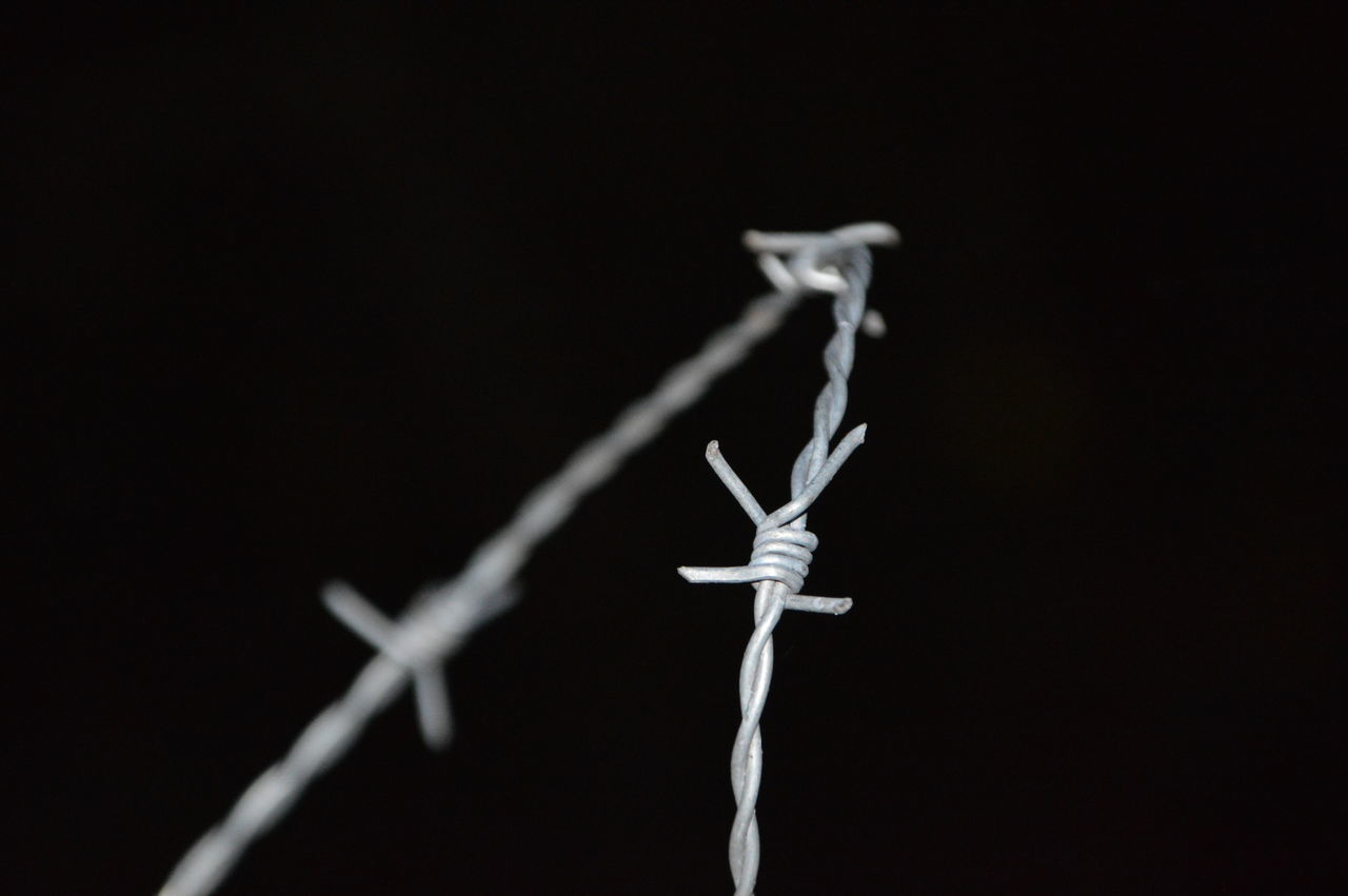 CLOSE-UP OF BARBED WIRE AGAINST SKY