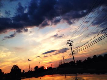 Low angle view of electricity pylon against cloudy sky