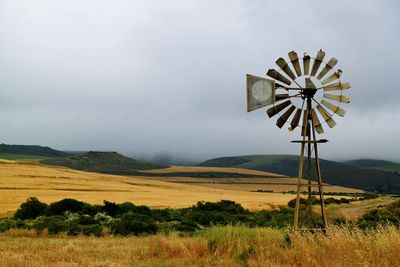 Wind turbines on field against sky