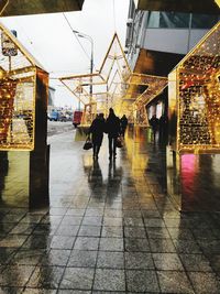 Rear view of people walking on street during rainy season