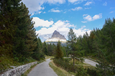 Road amidst trees and mountains against sky