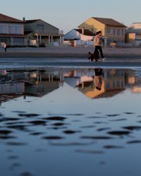 Reflection of woman on water in building against sky