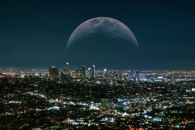 Aerial view of moon illuminated buildings against los angeles sky at night