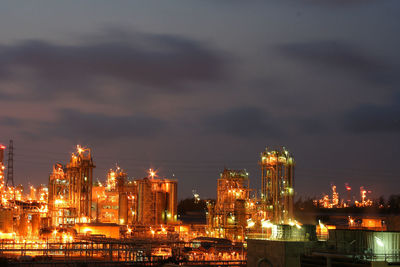 Illuminated cityscape by sea against sky at night