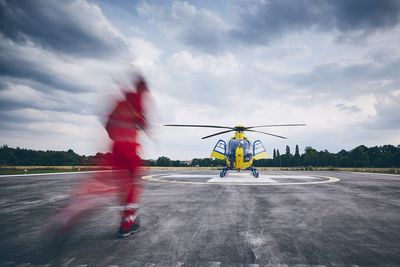 Ground crew running on airport runway against helicopter