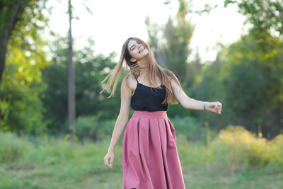 Young woman standing against trees