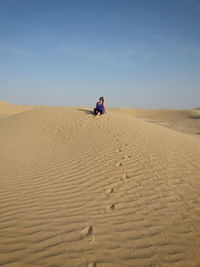 Woman on sand dune at desert against sky