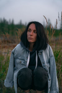 Portrait of beautiful young woman sitting on field