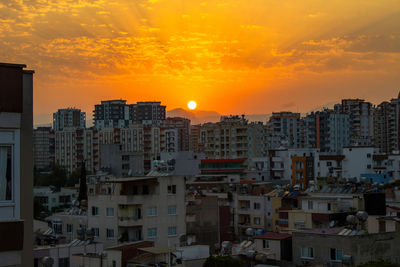 Buildings in city against romantic sky at sunset