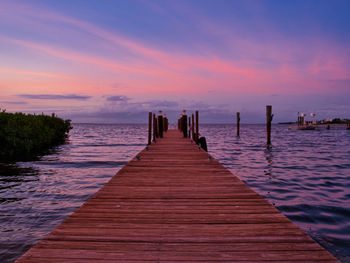 Wooden pier over sea against sky during sunset