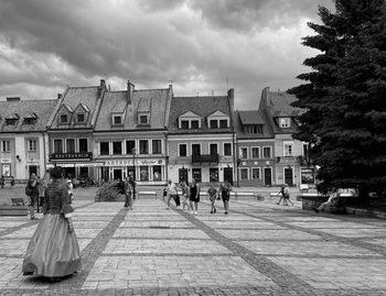 People by buildings in city against sky