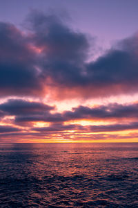 Scenic view of sea against dramatic sky during sunset