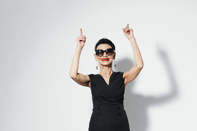 Young woman with arms raised against white background