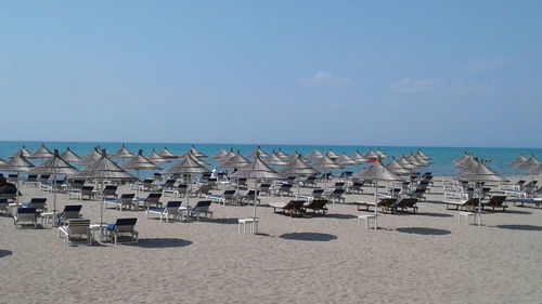 Panoramic view of lounge chairs on beach against sky