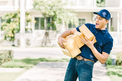 Delivery man holding cardboard boxes while standing outdoors