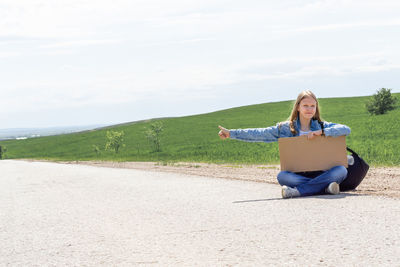 Full length of young woman exercising at beach against sky