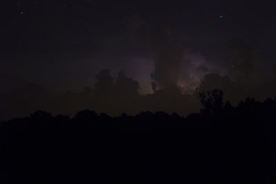 Silhouette trees on field against sky at dusk