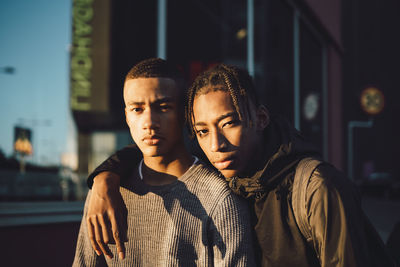 Portrait of confident friends standing in city during sunset