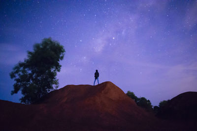 Silhouette man standing on mountain against sky at night