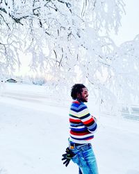 Side view of girl standing on snow covered field