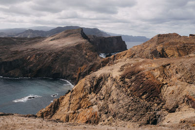 Hiking trail on dry rocks surrounded by the ocean on madeira