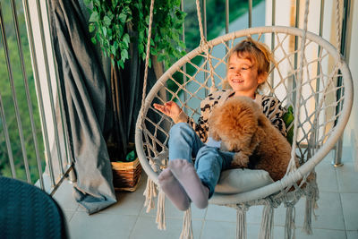 Happy little girl, child hugging with a smile her pet, poodle dog at home on balcony spring, summer