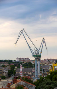 Cranes at construction site in city against sky