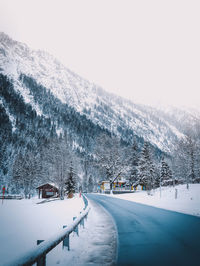 Snow covered road by mountain against sky