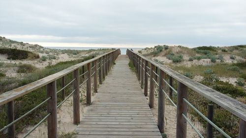 View of wooden footbridge leading towards the sea