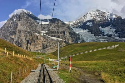 Railroad track amidst snowcapped mountains against sky