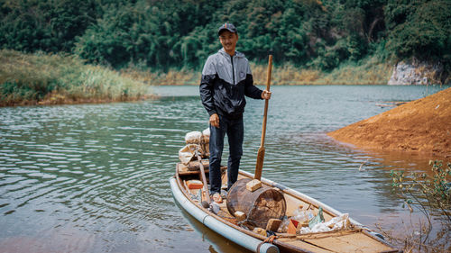 Man standing on boat against lake