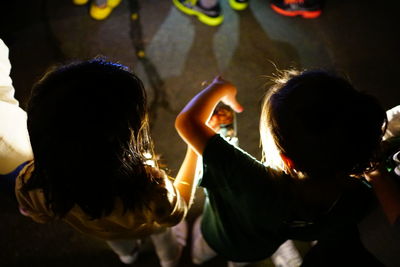 High angle view of girls holding illuminated lighting equipment at night