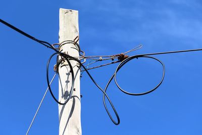 Low angle view of power lines against clear blue sky