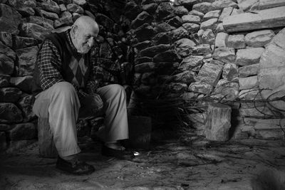 Rear view of man sitting by the wall